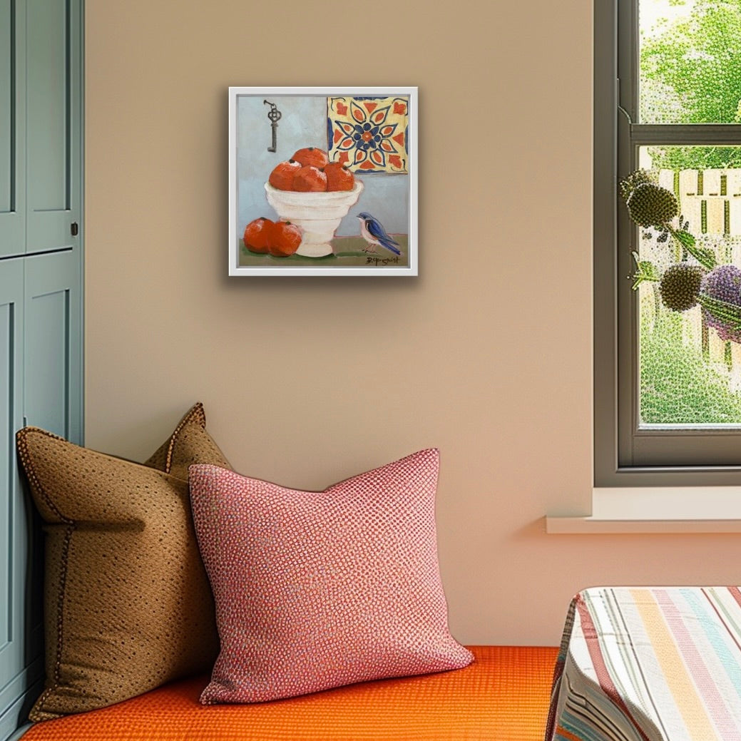 Decorative pillows on a bench with a framed original still life artwork above, near a window with outdoor view.